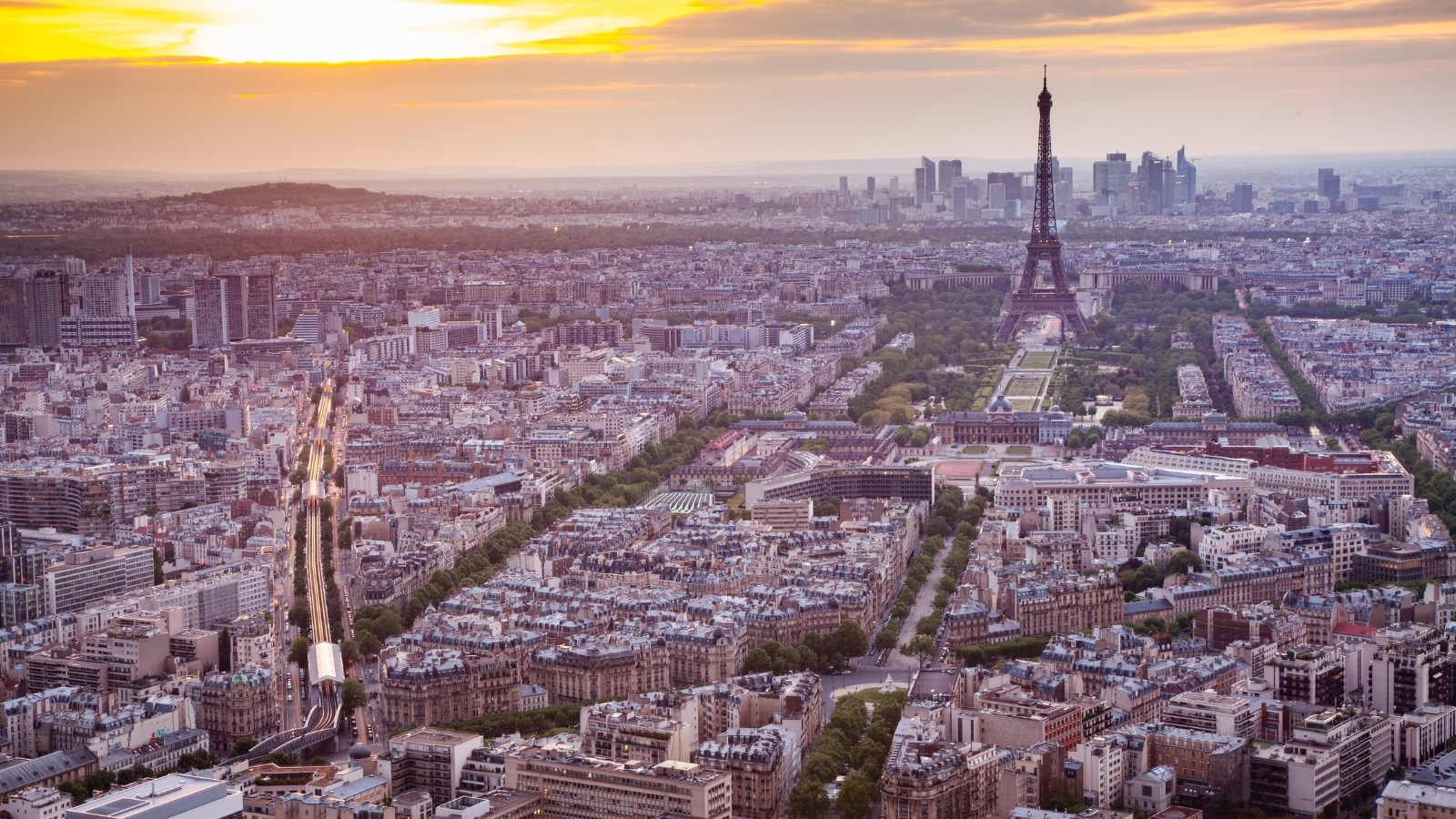 A photograph capturing the skyline of Paris, France, featuring the iconic Eiffel Tower prominently against the sunset backdrop. The image showcases the cityscape with various buildings and structures.