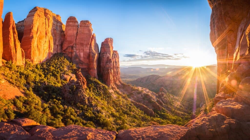 A photograph capturing the sunrise at Red Rock State Park in Sedona, Arizona. The image showcases the striking silhouette of rock formations against the early morning sky.