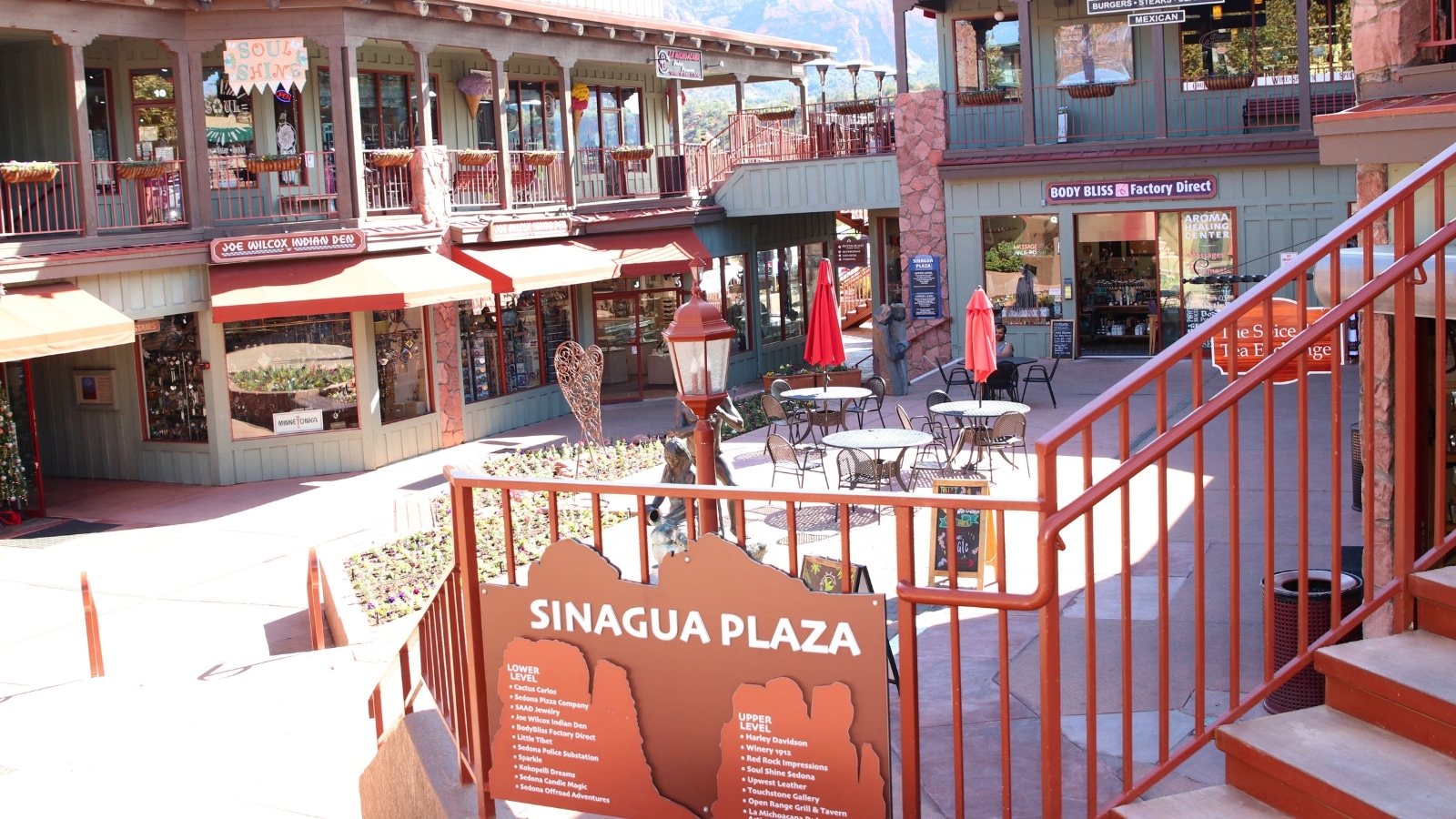 A photograph depicting a string of novelty gift shops and boutiques in uptown Sedona. Visitors can be seen walking along the sidewalk, suggesting pedestrian activity in the area.