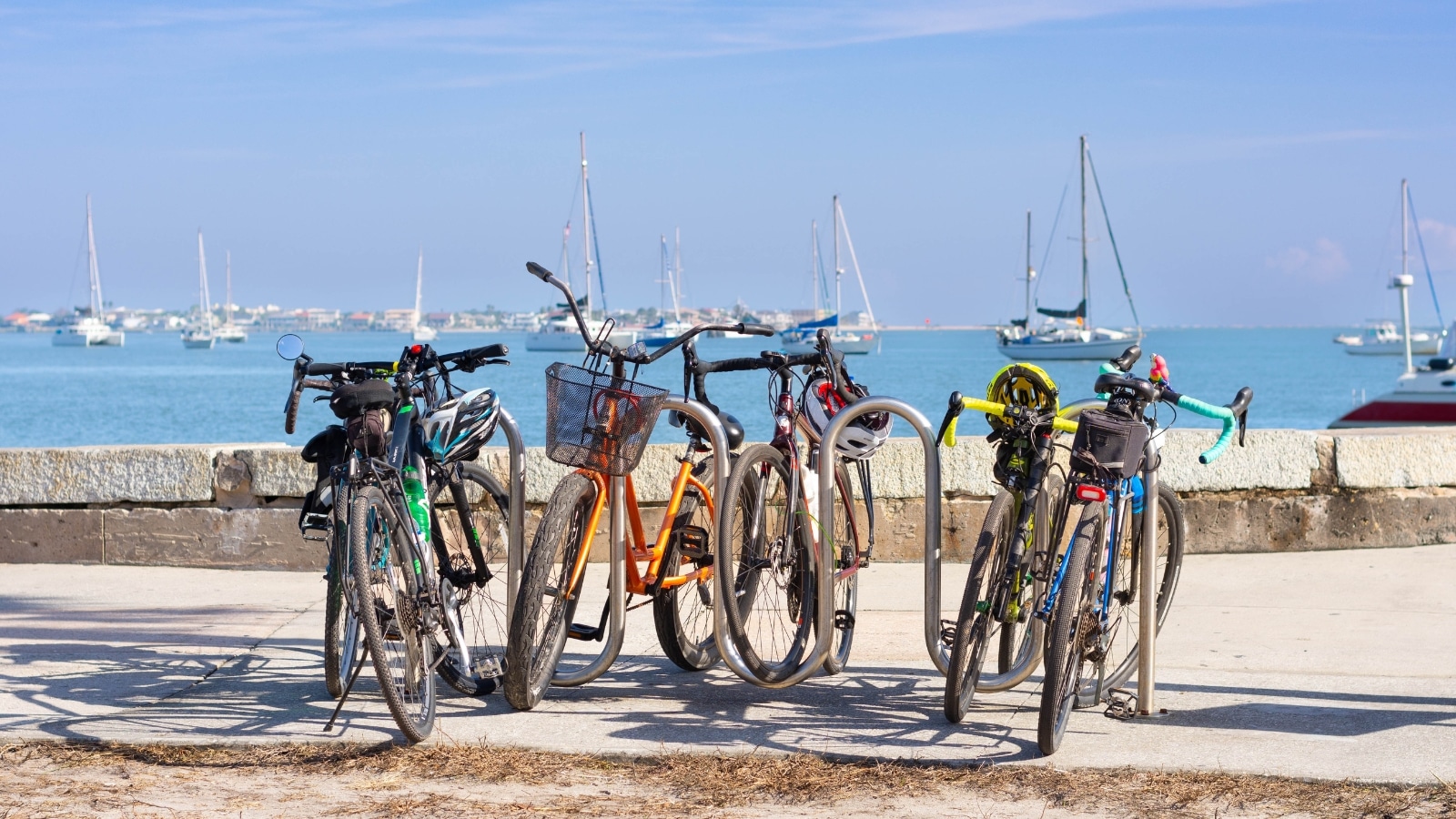 St. Augustine, Florida 6 bicycles of different colors are parked, in the background there is the sea, many white boats on the water.