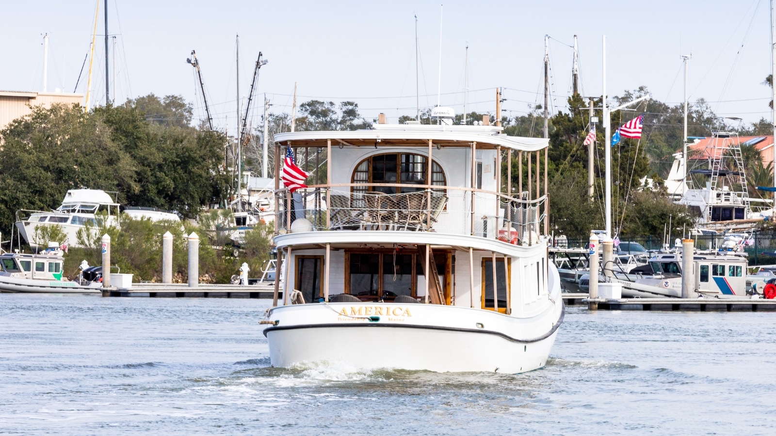 The image depicts a 2-story white tourist boat sailing toward the pier in St. Augustine, Florida, USA. The boat's exterior is a plain white color.
