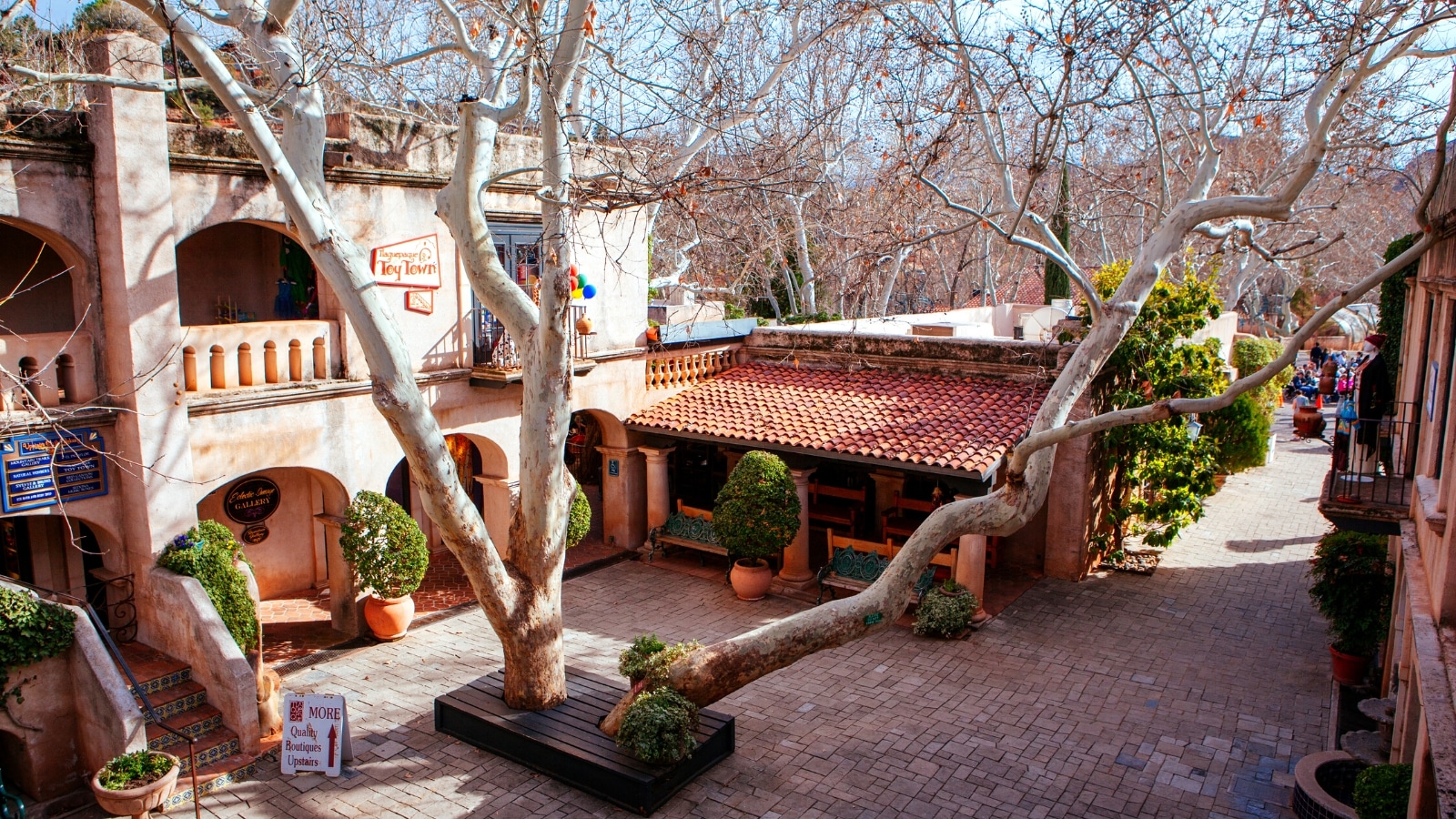 A photograph showcasing the iconic Tlaquepaque Arts & Crafts Village in Sedona, Arizona. The image highlights the village's stunning architecture, characterized by Spanish-inspired design elements such as arched doorways, red-tiled roofs, and intricate details.