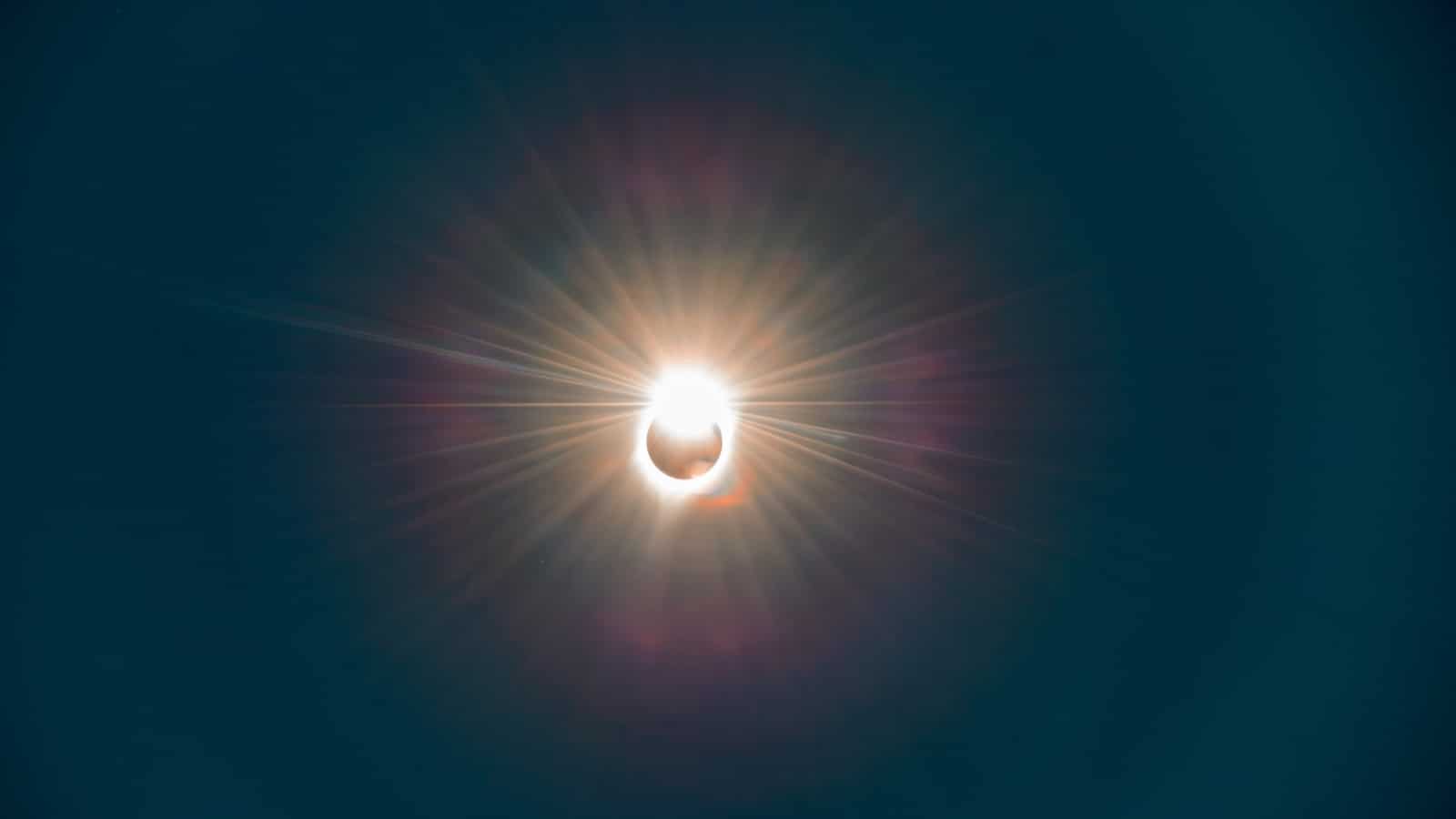 The image depicts a total solar eclipse, showcasing the sun being fully covered by the moon in the sky. The scene captures the phenomenon of the moon blocking the sun's light, creating a temporary darkness in the sky.