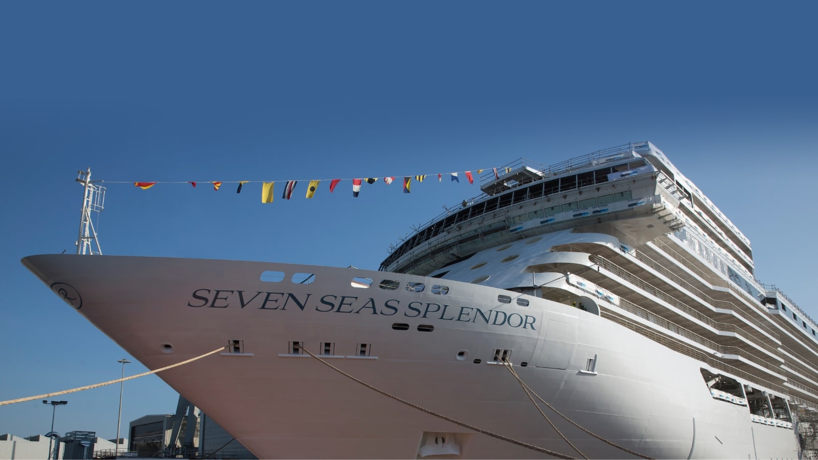 The image depicts a close-up view of a large ship moored, featuring the inscription "Seven Seas Splendor." The focus is on the ship itself, showcasing its size and design without including surrounding elements or activities.