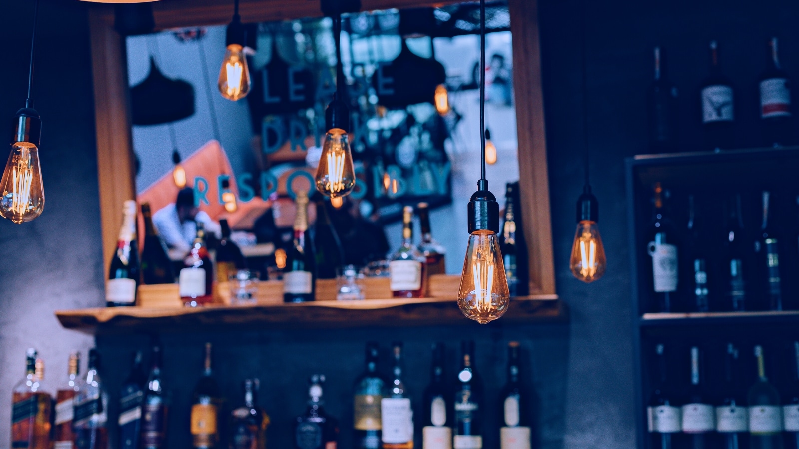 A photograph depicting various bottles of alcohol arranged on a stand. The image is intentionally blurred, making specific bottle details indistinct.