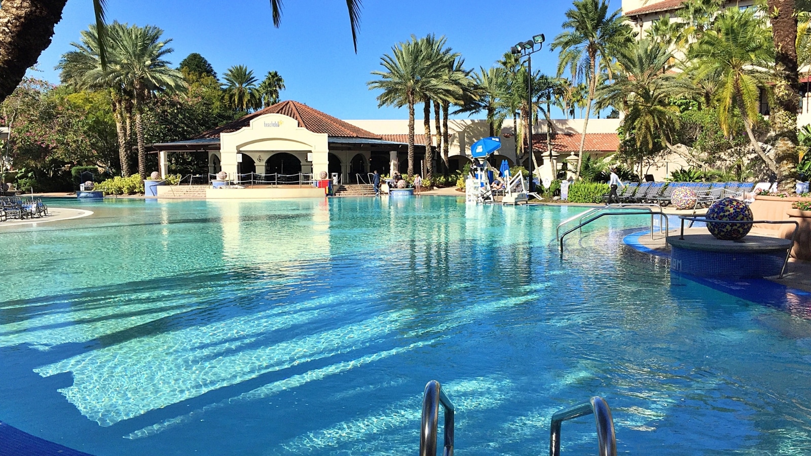 A photograph depicting a hotel pool. The image showcases a standard hotel swimming pool with a surrounding deck area and lounge chairs.