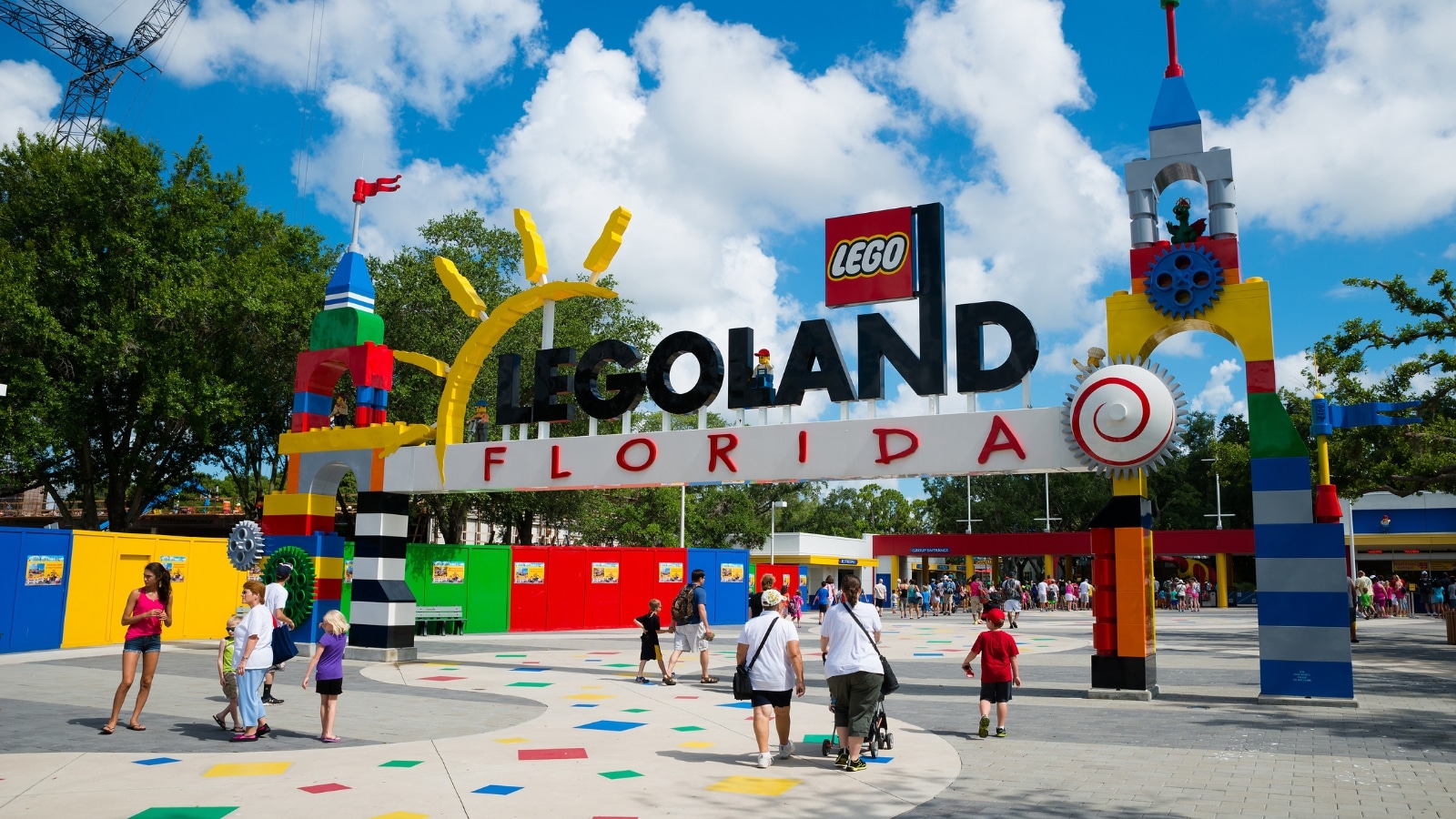 A straightforward image capturing visitors passing through the entrance to Legoland Florida. The entrance features standard elements associated with theme park aesthetics, including gates, signage, and ticketing infrastructure.