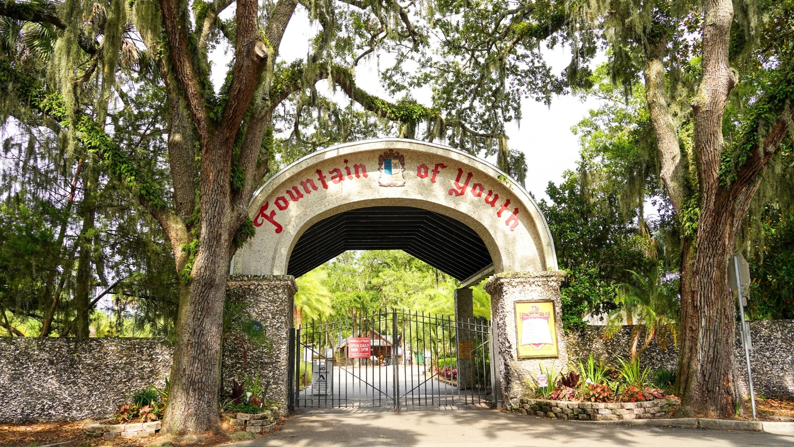 The image shows the entrance to the Fountain of Youth in St. Augustine, Florida, surrounded by abundant greenery and trees.