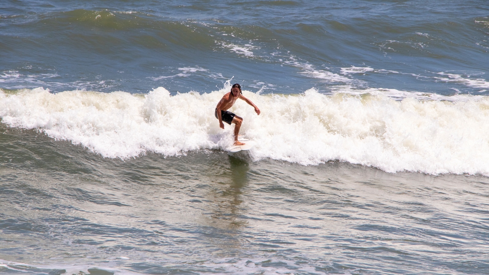 The image depicts a surfer on a board riding a wave in St. Augustine, Florida. The surfer is positioned in the center of the frame, with the wave curling behind them.