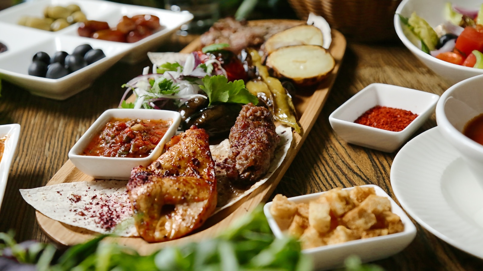 The image features a wooden table adorned with several plates of appetizing food. The table setting appears inviting, showcasing a range of flavors and presentations.