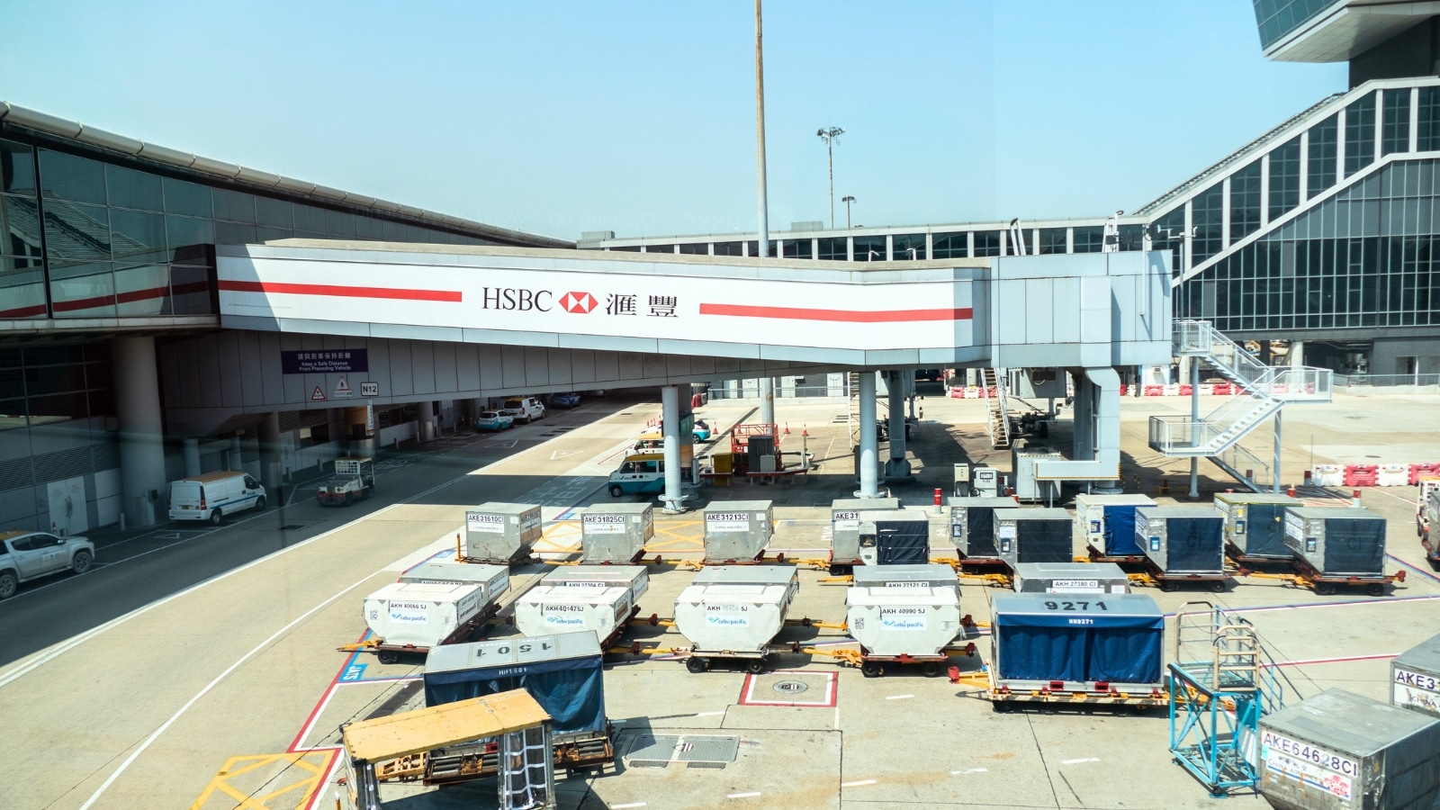 The image features Hong Kong International Airport with numerous cargo containers visible on its premises.