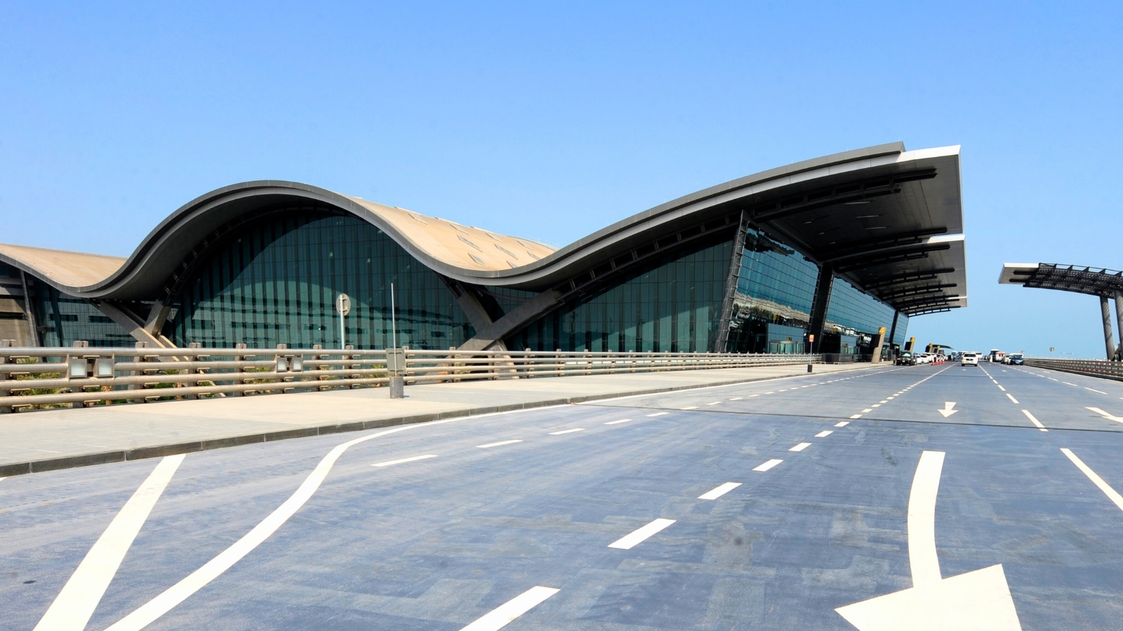 The image showcases the exterior view of the passenger terminal complex at Hamad International Airport in Doha, Qatar. The architecture of the terminal features a modern and functional design, reflecting the airport's status as a major transportation hub.