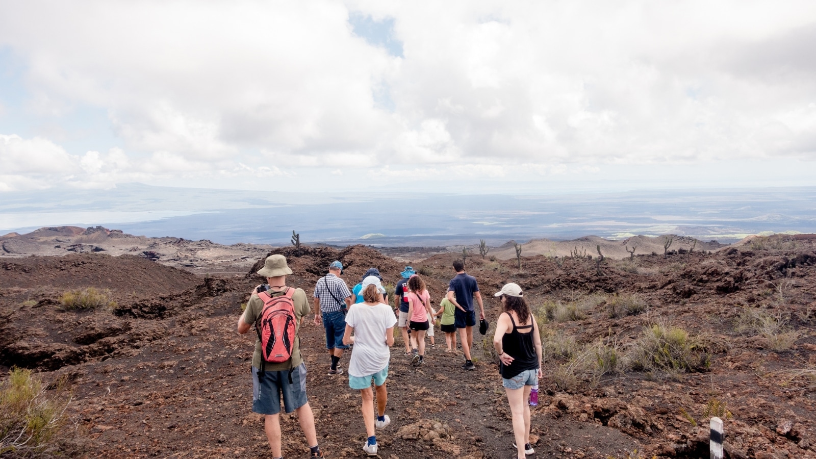 The image captures people hiking along Sierra Negra, a significant shield volcano located at the southeastern end of Isabela Island in the Galapagos Islands, Ecuador.