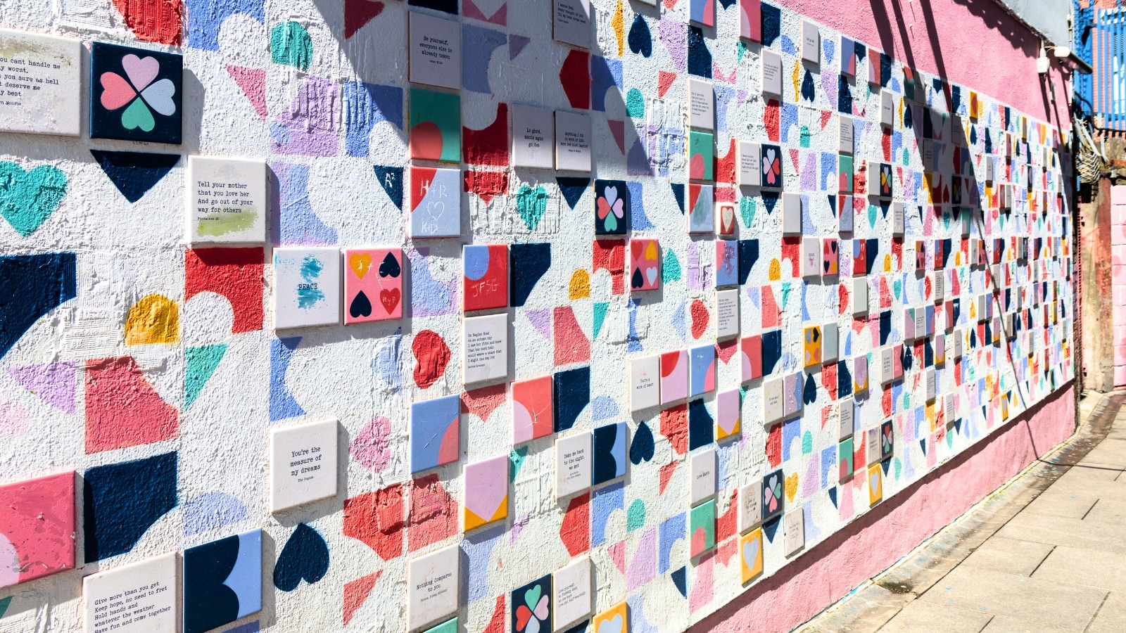 The image captures Love Lane, a downtown alley in Temple Bar, Dublin, Ireland, adorned with artistic graffiti known as the "Wall of Love." The graffiti includes quotes from movies, local sayings, and famous loving words, creating a colorful and expressive display.
