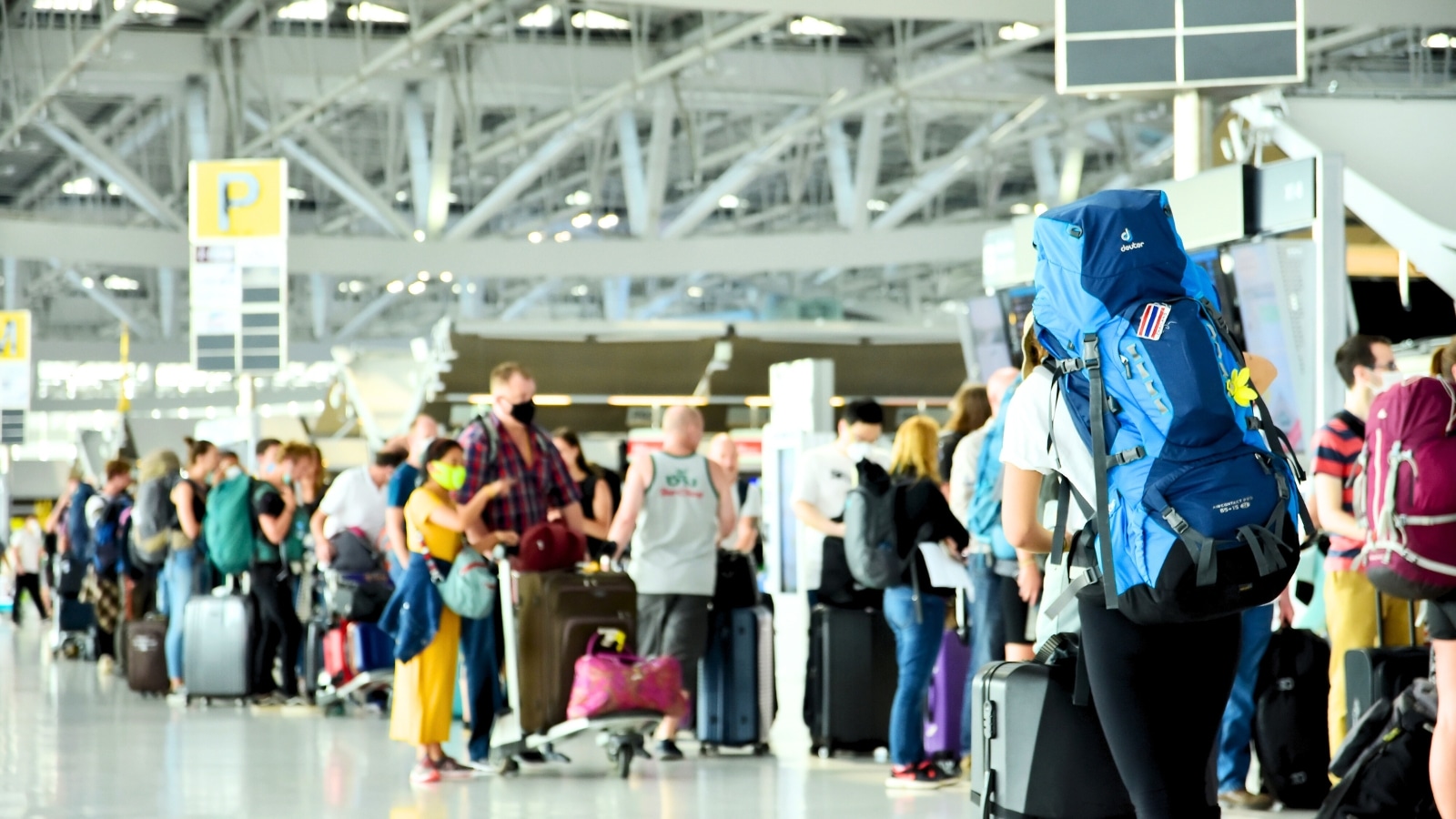 The image depicts a scene at an airport where many tourists are waiting in line to check in for their flights. The check-in area is busy, with multiple queues formed as passengers prepare to go through the check-in process. Travelers can be seen carrying luggage and personal belongings, indicative of the airport's bustling activity. The airport environment is characterized by its structured layout, with signage and staff assisting passengers with the check-in procedure. Overall, the image captures the typical experience of travelers at an airport as they navigate through the check-in process before their flights.
