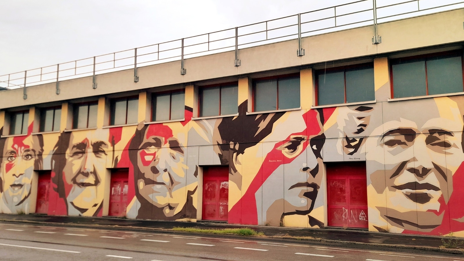 The image captures murals in Milan's Ortica district, showcasing various themes such as cooperation, legality, women of the 20th century.