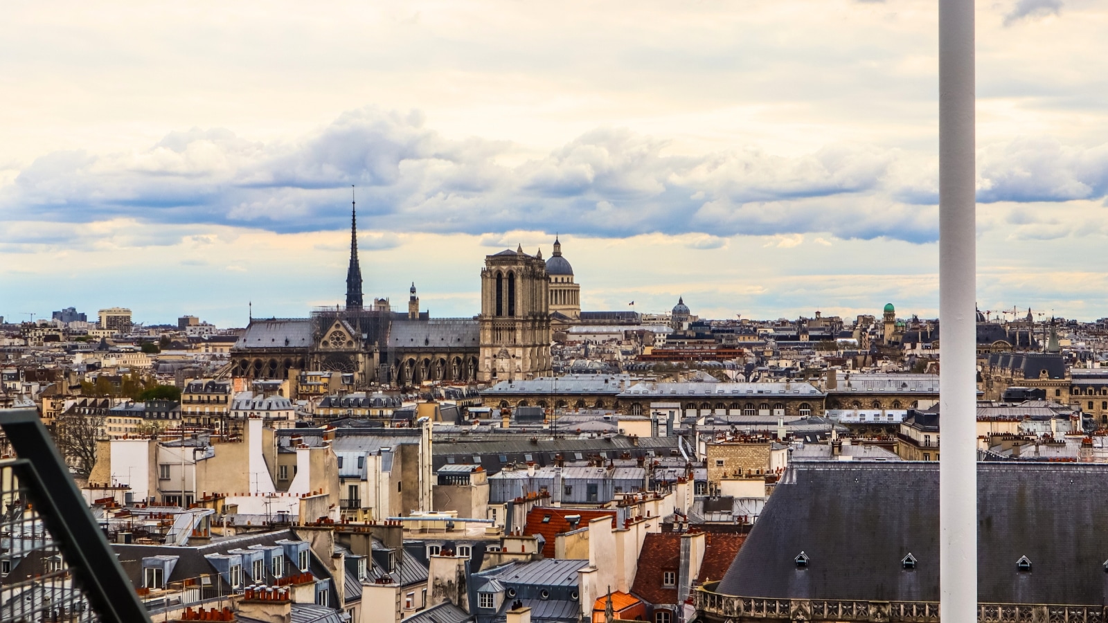 The image captures a view of Notre Dame Cathedral and the cityscape from the Centre Pompidou in Paris, France. The scene features the distinctive architecture of Notre Dame, with its gothic spires and intricate details.
