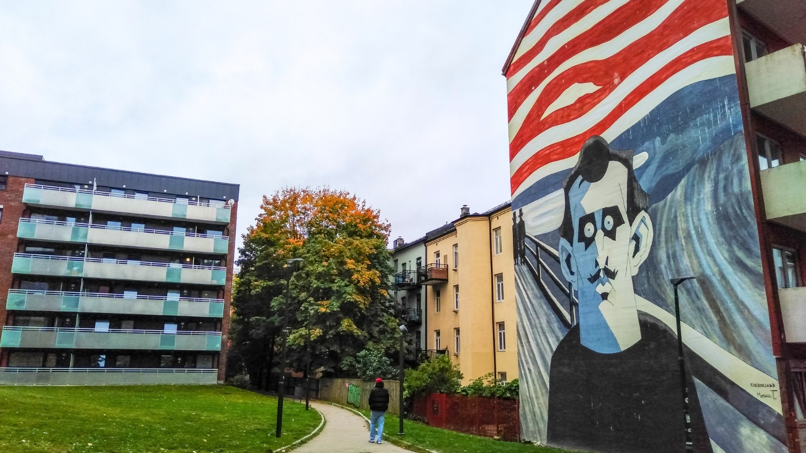 The image captures the exterior of a building in the Grunerlokka district of Oslo, Norway, featuring street art in the form of graffiti covering the wall. The graffiti is extensive, with various artistic expressions and colors displayed throughout the facade of the house.