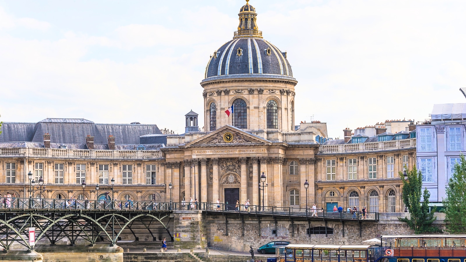 The image captures the Pont des Arts and The Institut de France along the Seine River in Paris, France. The Institut de France, showcasing classical French architecture with its domed roof and intricate details.