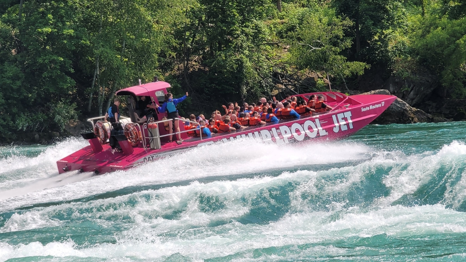 The image captures a group of tourists enjoying a sightseeing cruise near Niagara Falls, with a focus on the Whirlpool jet boat tours.