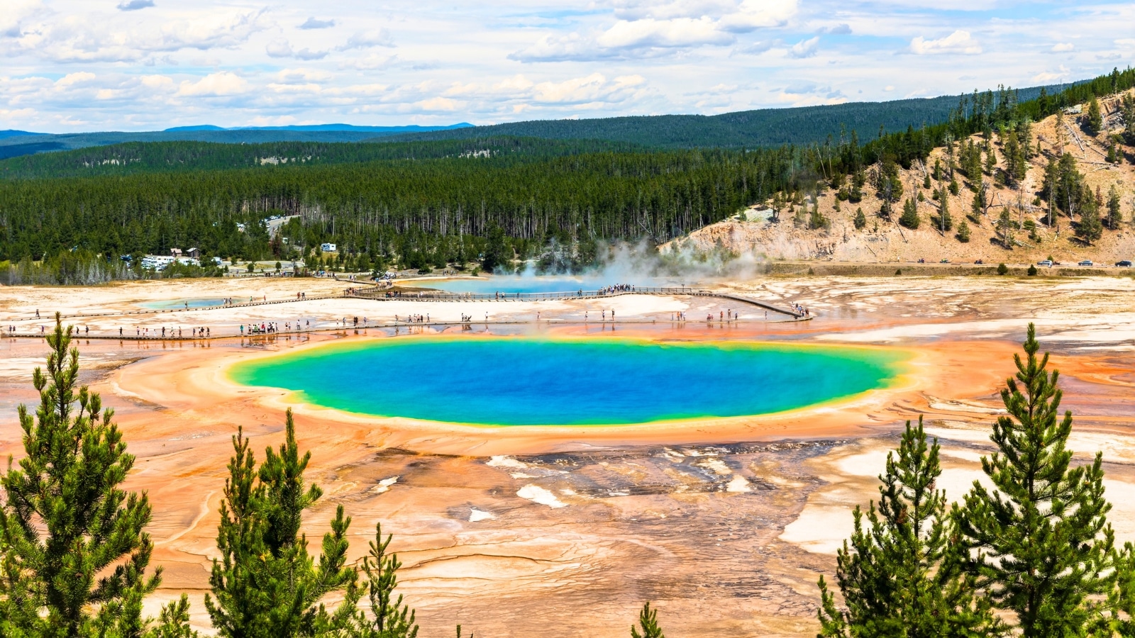 The image depicts the Grand Prismatic Spring in Yellowstone National Park, showcasing its vibrant colors and unique geological features.
