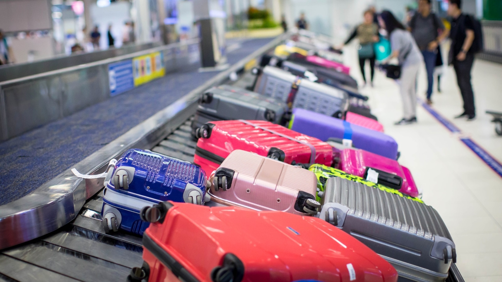 baggage carousel at an airport, with numerous suitcases of varying colors circulating on the baggage claim belt.