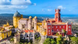 The image captures a top view of the Pena Palace in Sintra, near Lisbon, Portugal, taken from a flying drone. From this aerial perspective, the palace
