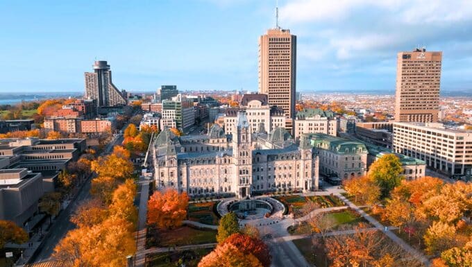 The image presents a view of Hartford, Connecticut, during autumn, characterized by yellow-orange leaves on the trees. The cityscape features a blend of buildings and urban infrastructure.