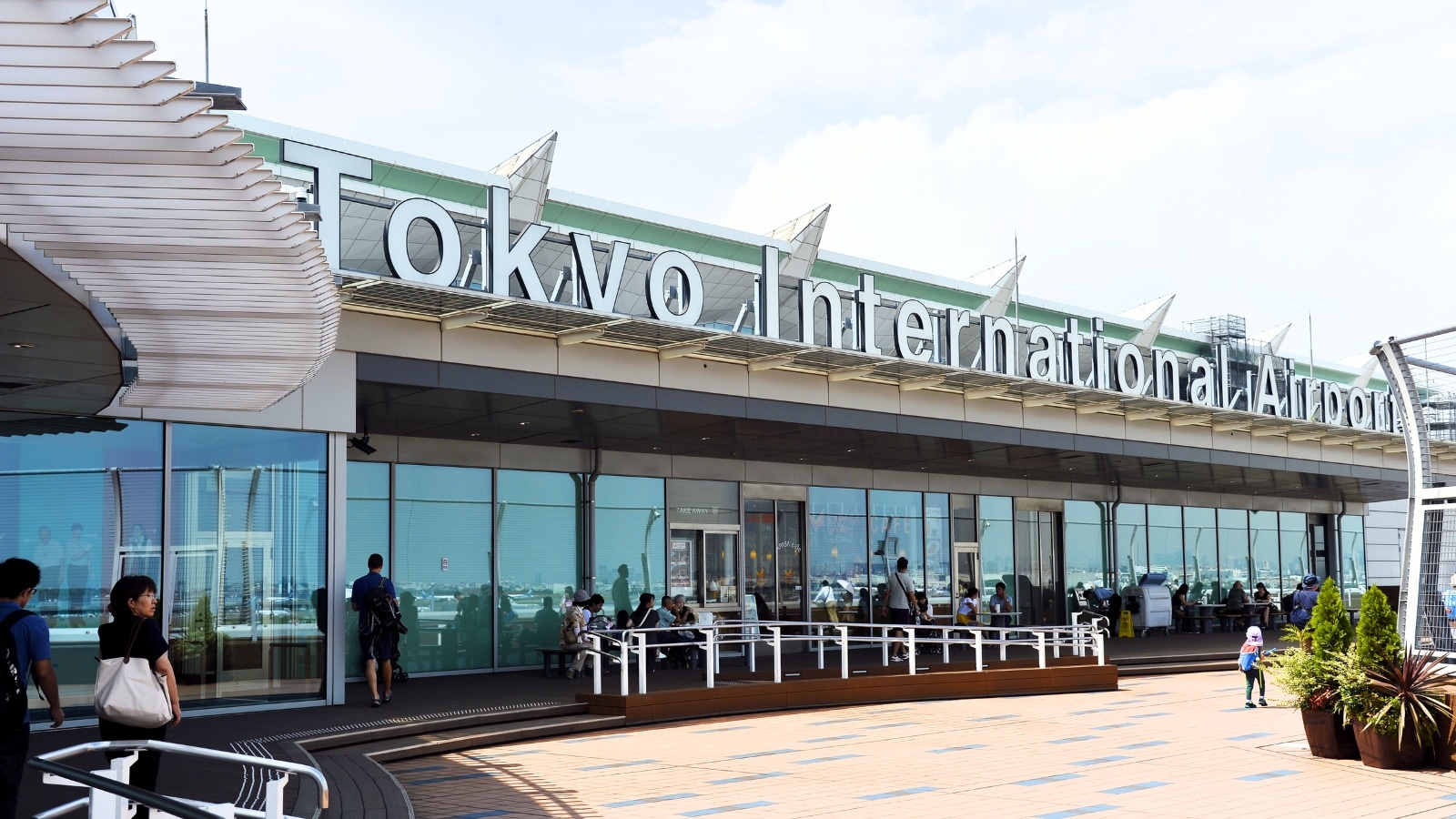 The image presents a close-up view of Tokyo Haneda Airport, prominently displaying the words "Tokyo International Airport" in large letters.