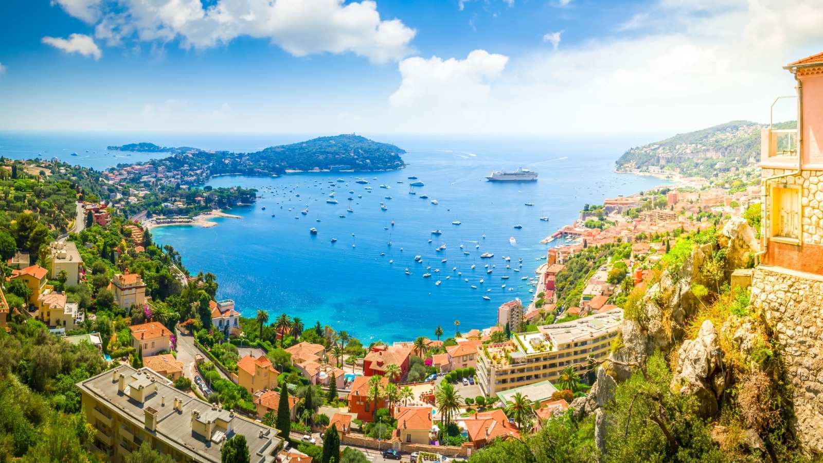 View of a small yet beautiful beach in Antibes, situated on the French Riviera and Côte d'Azur between Cannes and Nice. The scene overlooks a creek filled with numerous boats. In the foreground, the cityscape features historical brown houses.