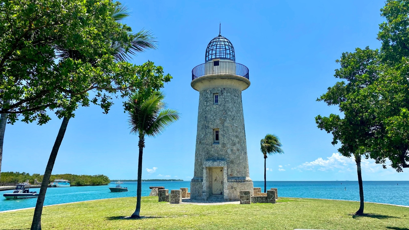Biscayne National Park in Florida features a stone lighthouse situated on an island. The lighthouse, constructed from light-colored stone, stands tall against the backdrop of the blue sky and ocean.