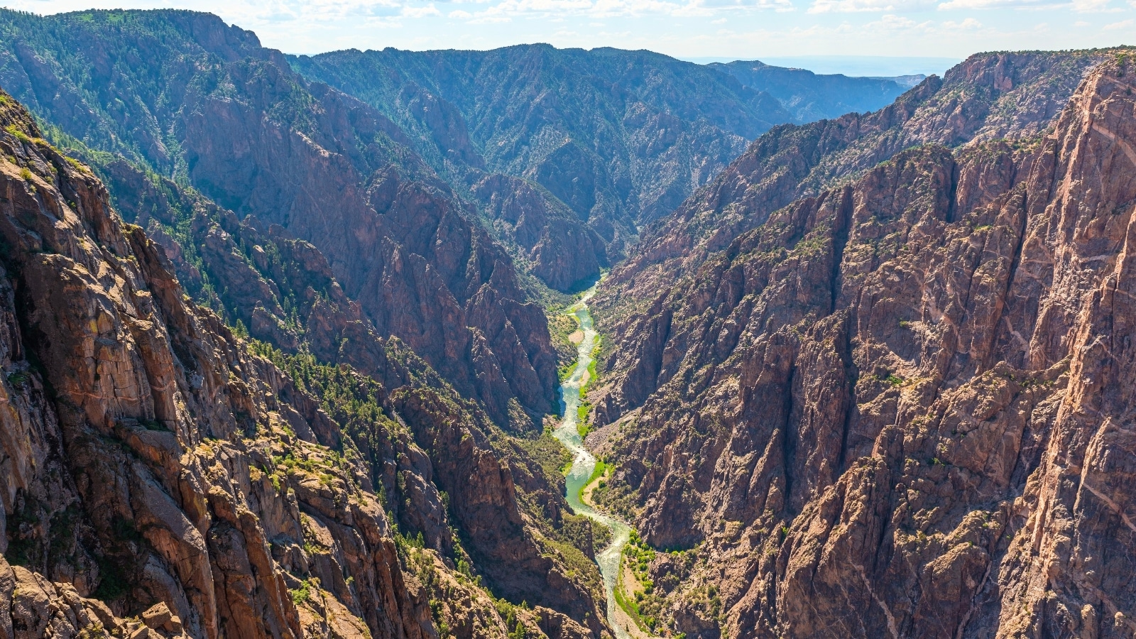 In the depths of Black Canyon of the Gunnison National Park, Colorado, the Gunnison River flows serenely, carving through rugged canyon walls.
