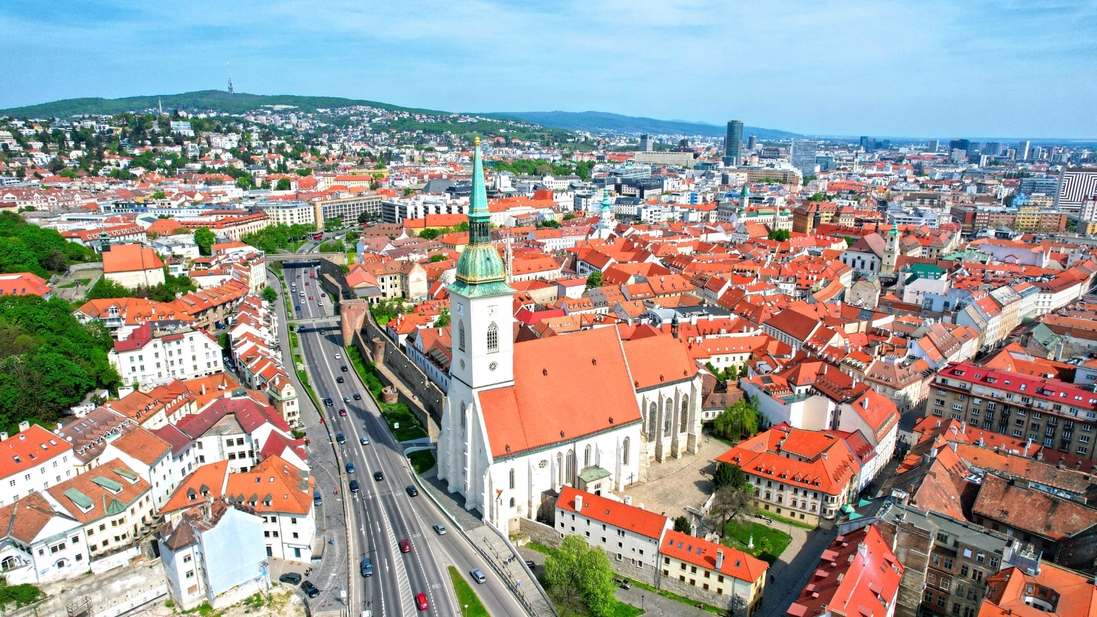 The image shows St. Martin's Cathedral in Bratislava, Slovakia, viewed from above. The surrounding houses feature roofs of a uniform brown color.