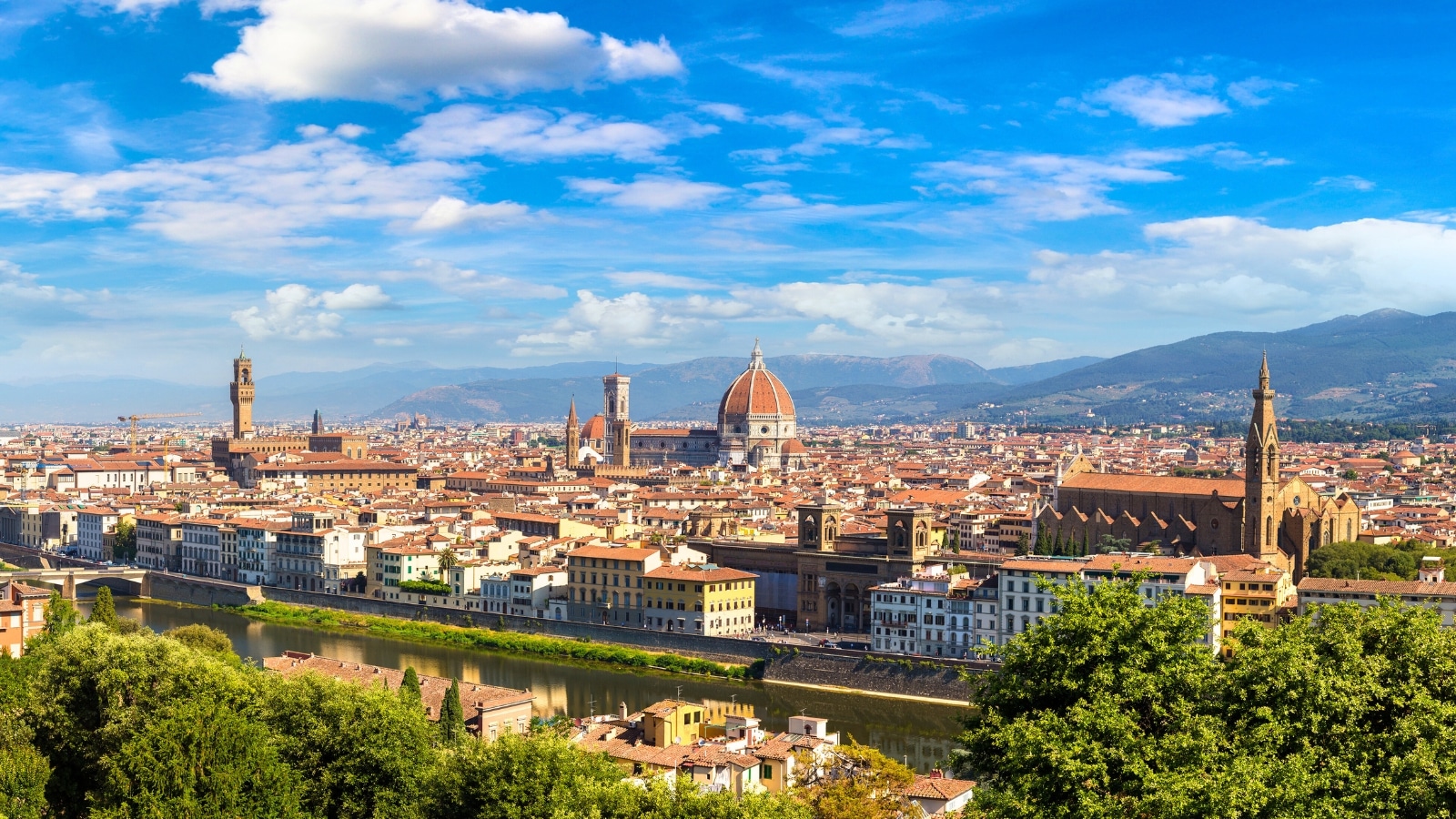 The panoramic view captures the Santa Maria del Fiore Cathedral in Florence, Italy. The cathedral boasts a magnificent dome and intricate Gothic architecture. Surrounding the cathedral are historic buildings and bustling streets.