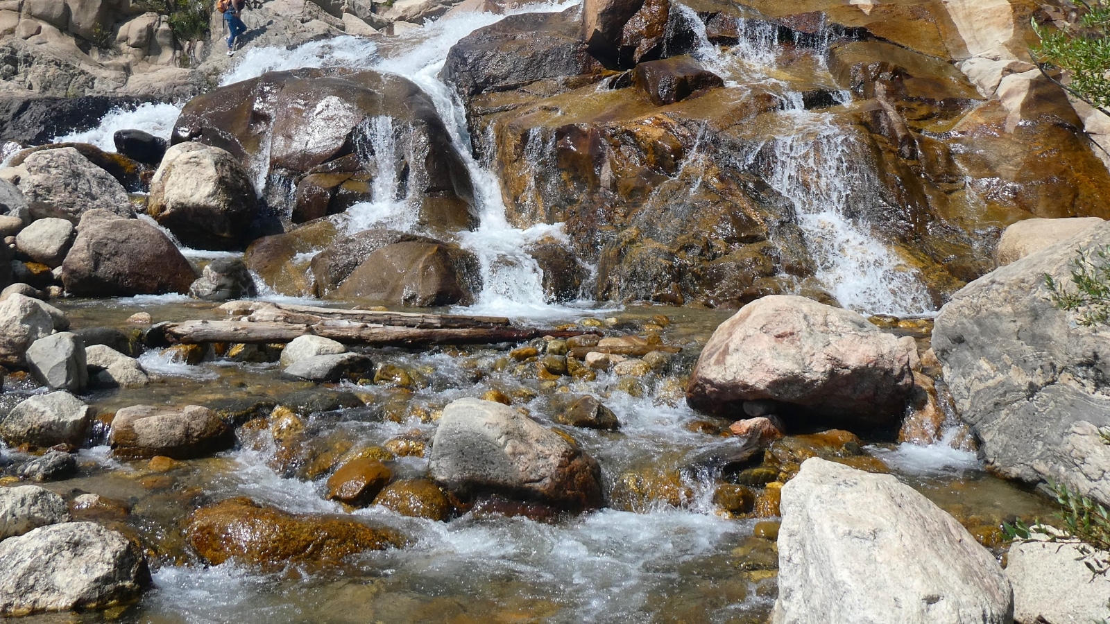 The image depicts a small waterfall cascading over rocks in a natural setting.