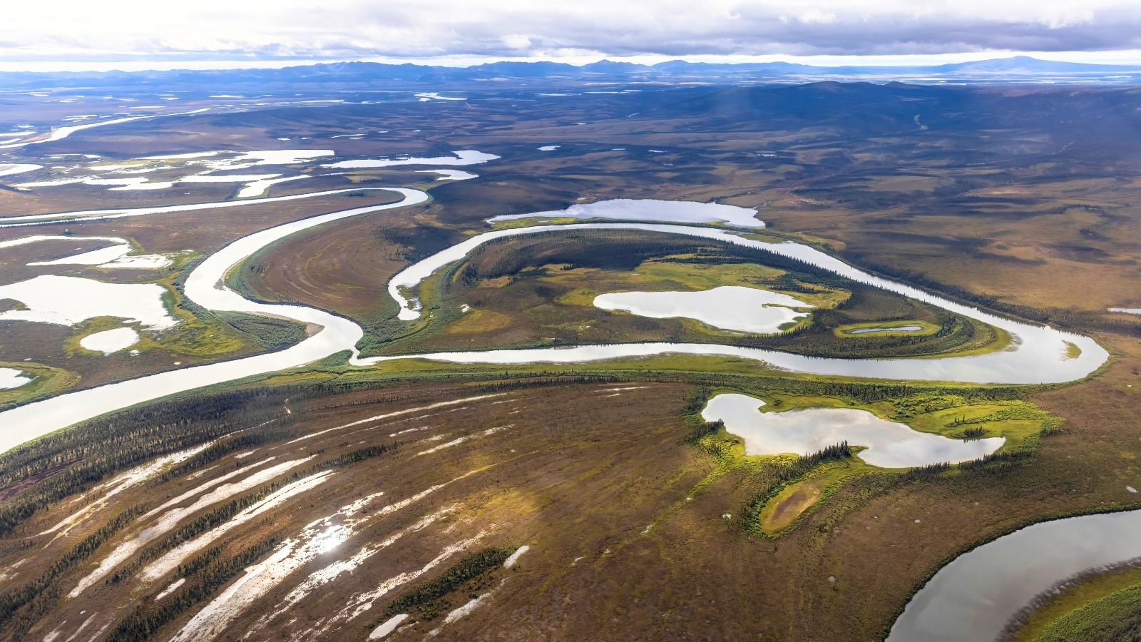 Kobuk Valley National Park located in the Arctic region of Alaska. The scene captures the vastness and rugged beauty of the park, characterized by long winding rivers that traverse the pristine wilderness.