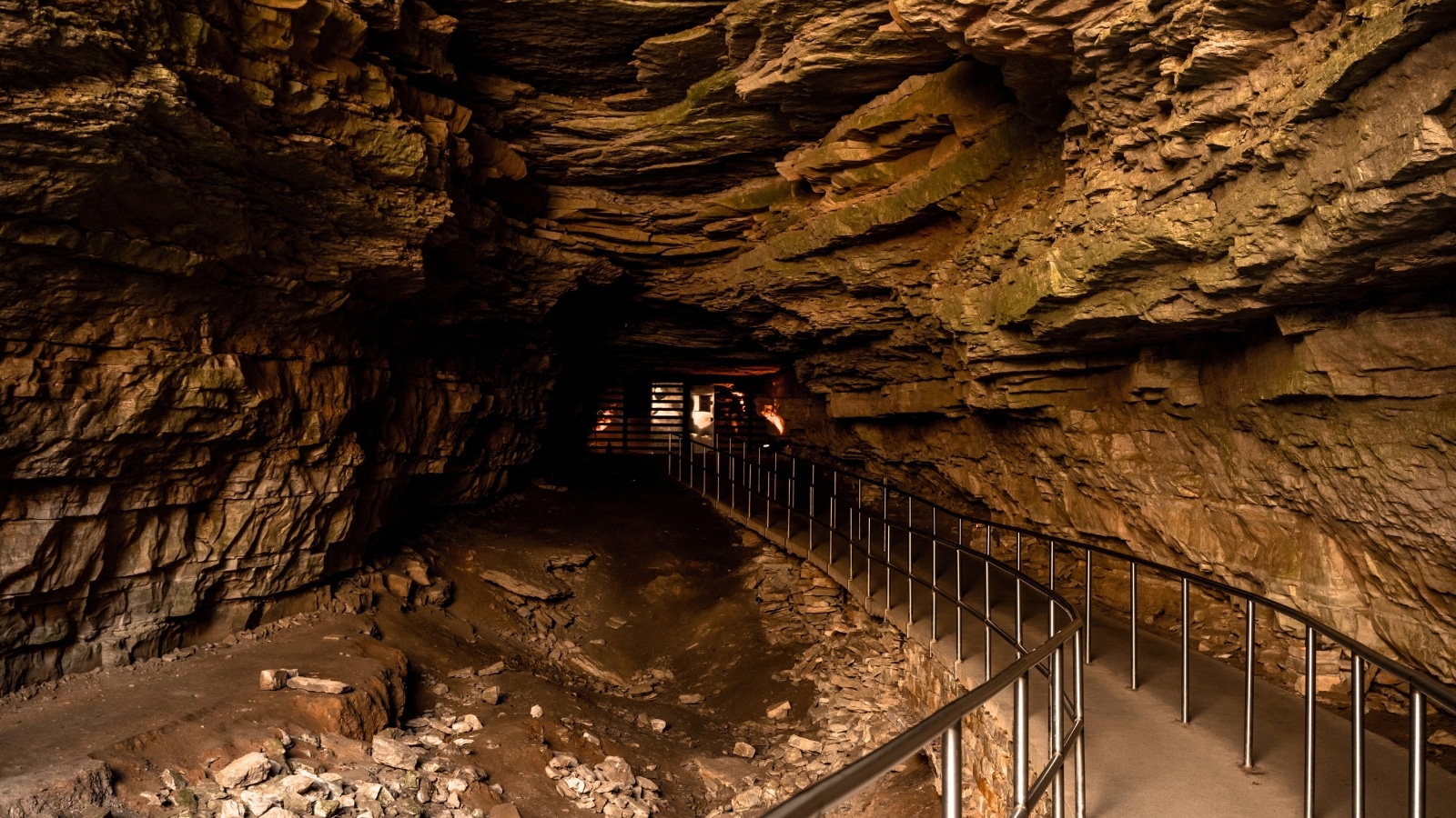 Mammoth Cave National Park in Kentucky features the historic entrance to Mammoth Cave with a long sidewalk ramp. The entrance consists of a large, dark cave.