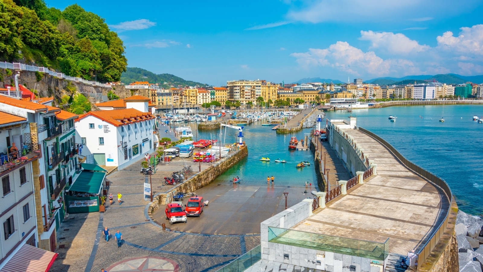 Spanish port of San Sebastian, Spain, with numerous boats docked in the harbor. The marina features a mix of sailboats, yachts, and other watercraft.