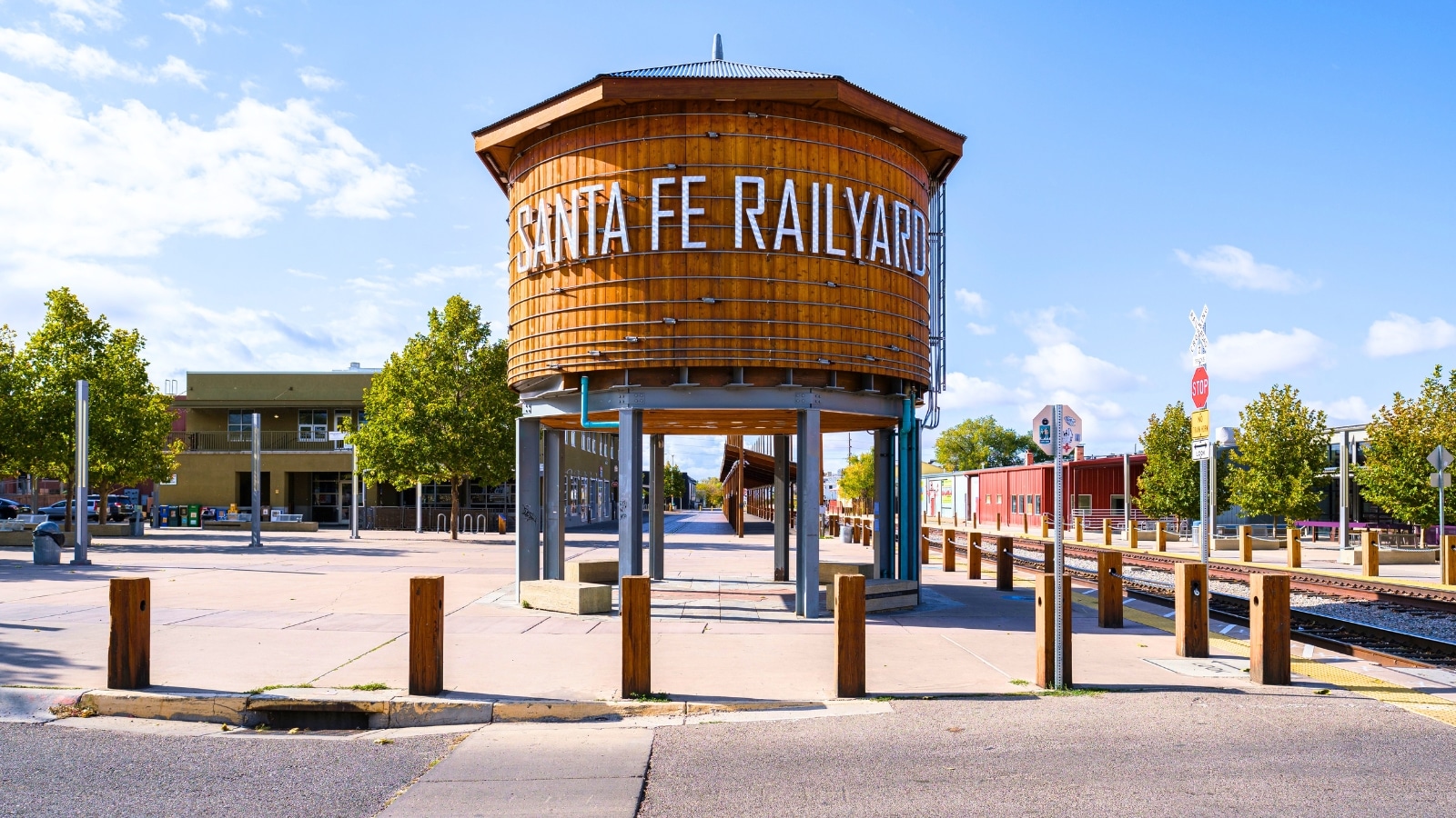 On a hill in Santa Fe, New Mexico, a prominent metal structure supports a large wooden barrel with a roof, prominently displaying the words "Santa Fe Railyard."