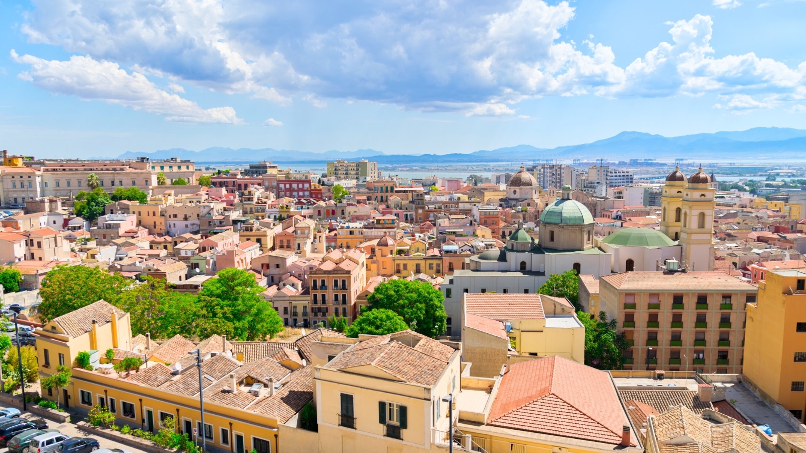 Cagliari, the capital of Sardinia, Italy. The cityscape features beige-brown houses of various shapes, exuding a historical charm. These buildings contribute to the distinctive appearance of the area, reflecting traditional architectural styles. The sky above is adorned with large clouds.