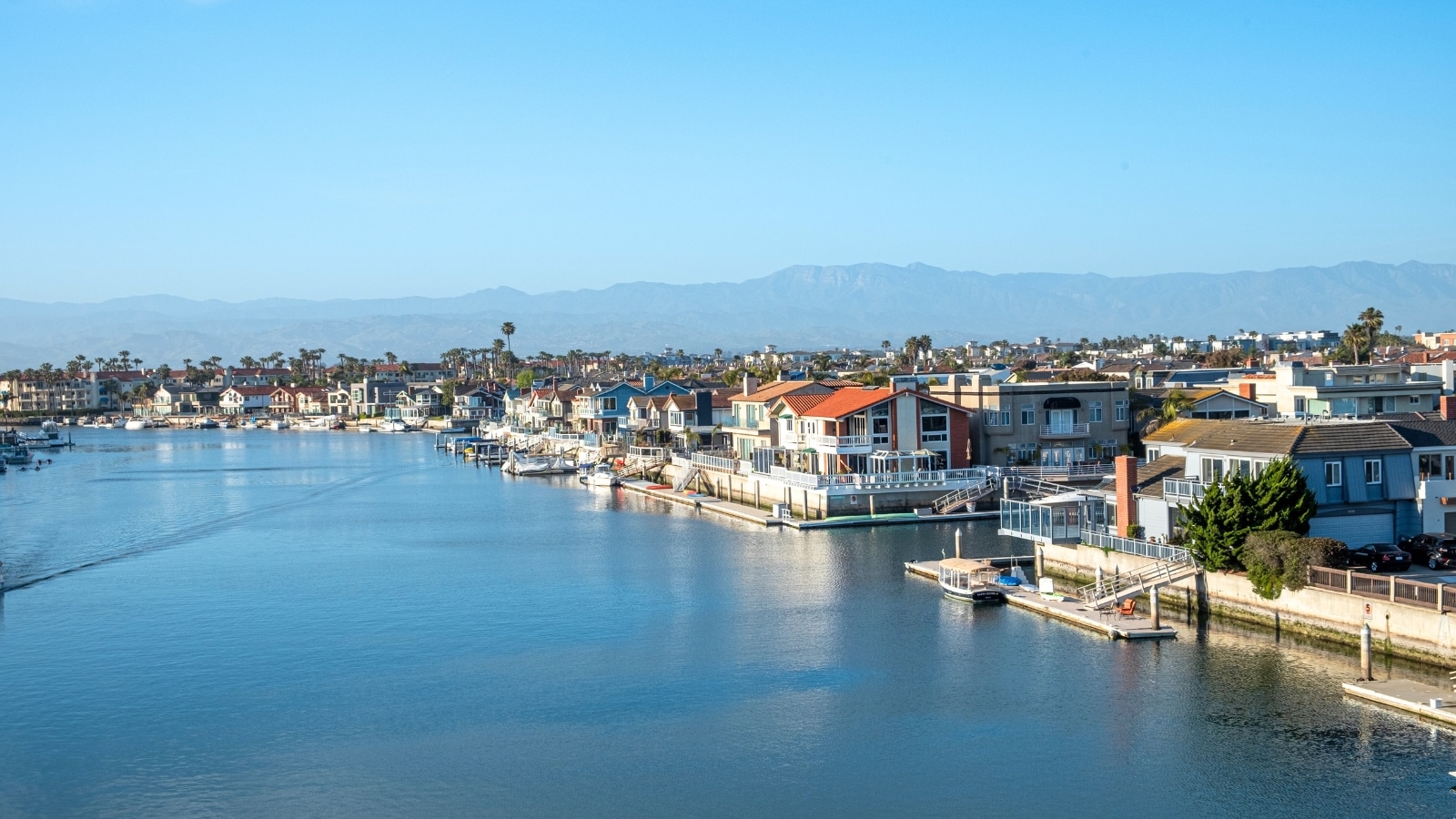 Ventura, USA, offers a scenic view of old houses along the beach promenade and an artificial channel. The artificial channel adds a nautical element, lined with boats and marine structures.