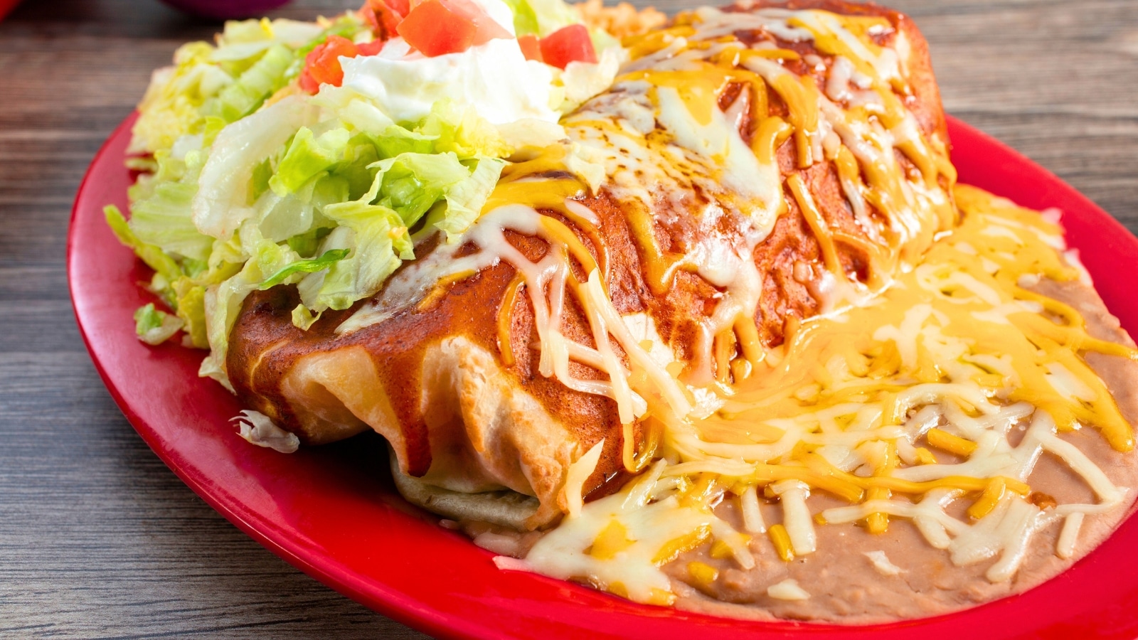 The close-up view showcases a burrito plate featuring a generous serving of salad and melted cheese.