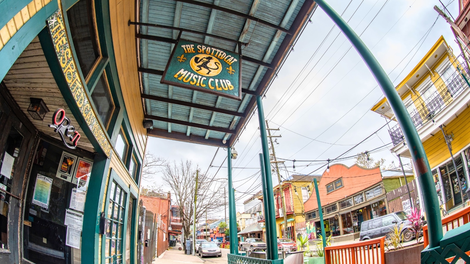 The entrance of the Spotted Cat Jazz Club in New Orleans, LA, features a green door. A visible sign reads "Spotted Cat Jazz Club,".