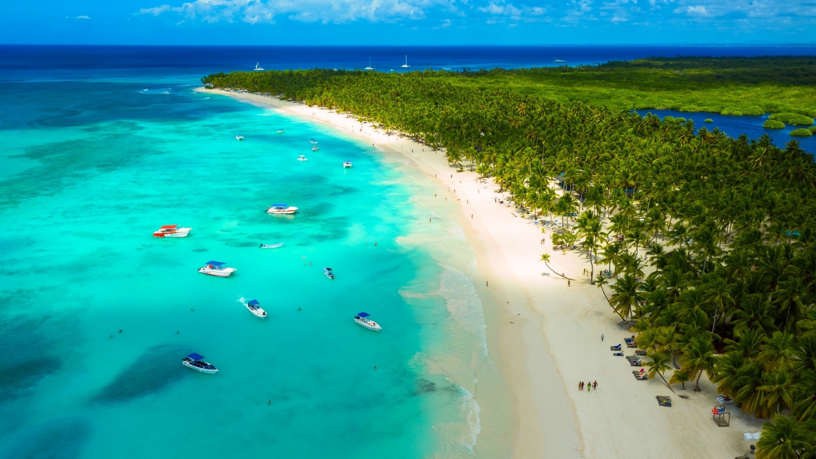 A beautiful Caribbean beach is depicted in the image, showcasing an aerial view of a tropical idyllic summer landscape. The beach features white sand along the sea coast, with clear blue waters stretching out to the horizon.
