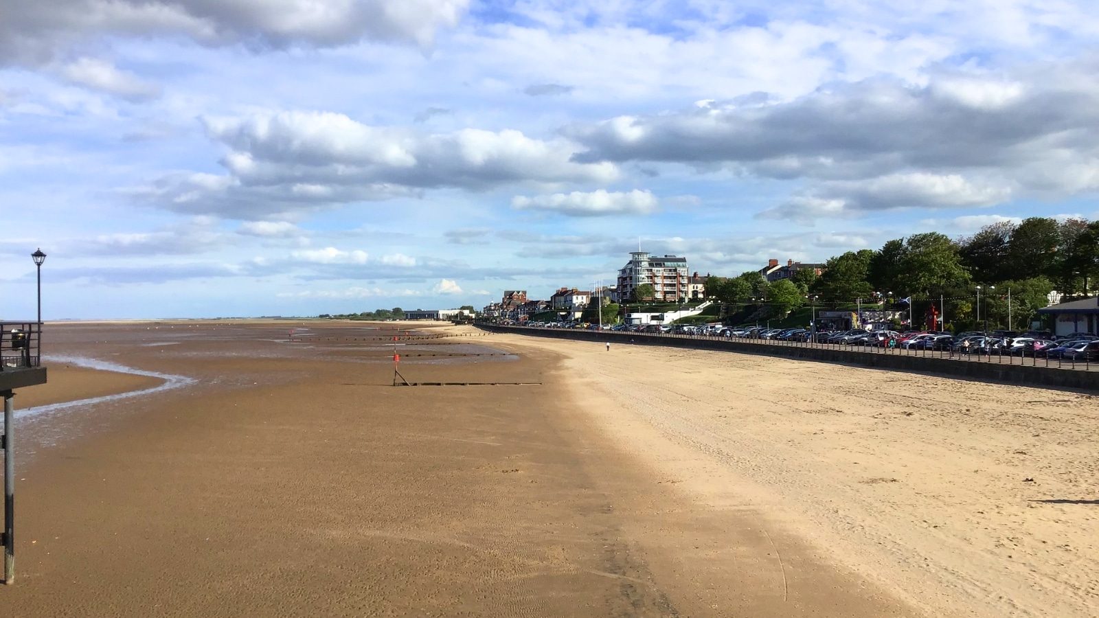 Cleethorpes beach, with the town in the background, presents a wide sandy shoreline on the left, contrasting with the urban landscape of the town on the right.
