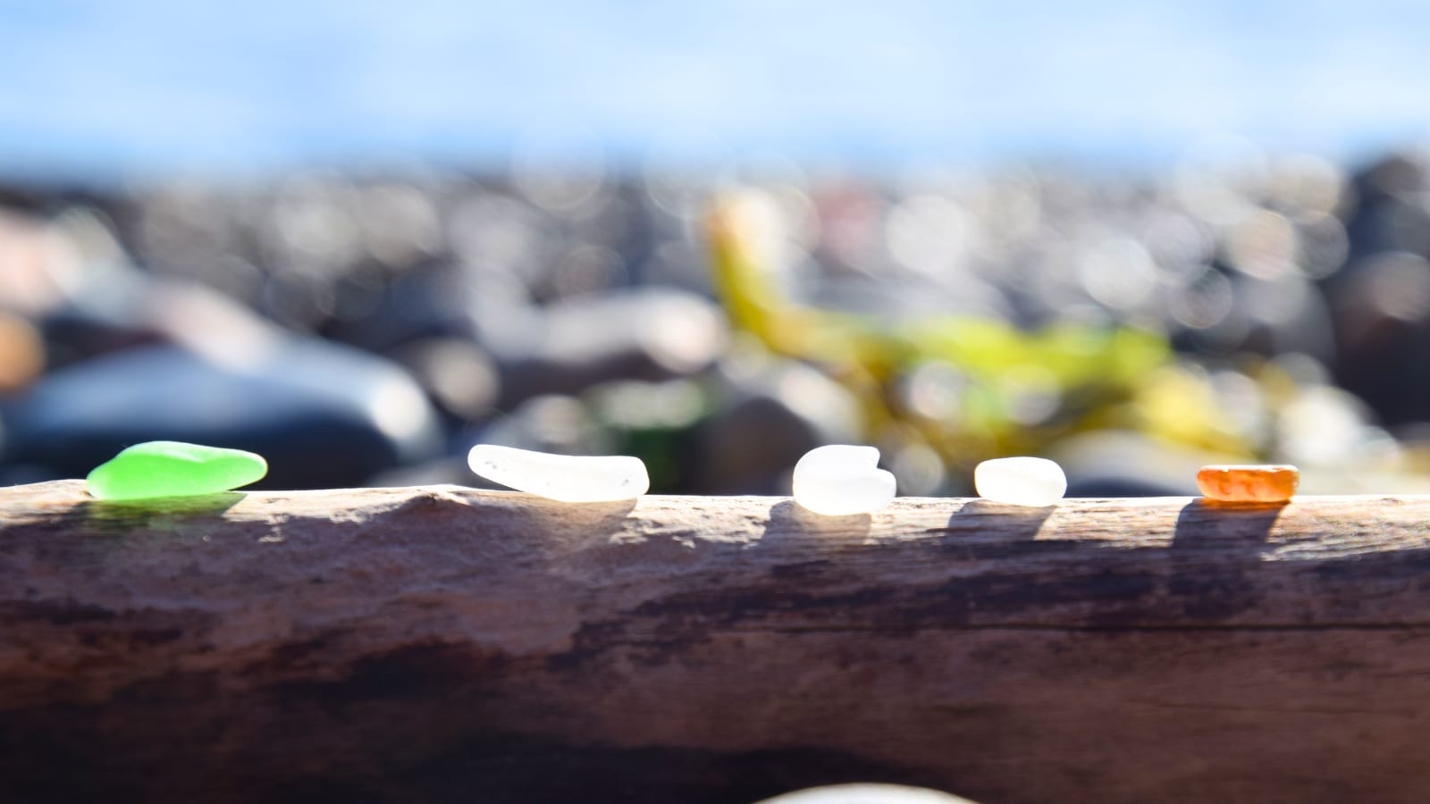 Rosario Beach on Fidalgo Island in Washington State is depicted in a photo focused on beach glass, with the background intentionally blurred.