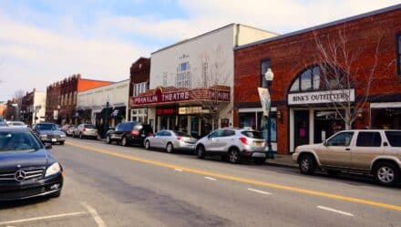 Main Street in Franklin, Tennessee showcases classic brick buildings, the famous Franklin Theater, various shops and restaurants, and various parked cars along the sidewalks.
