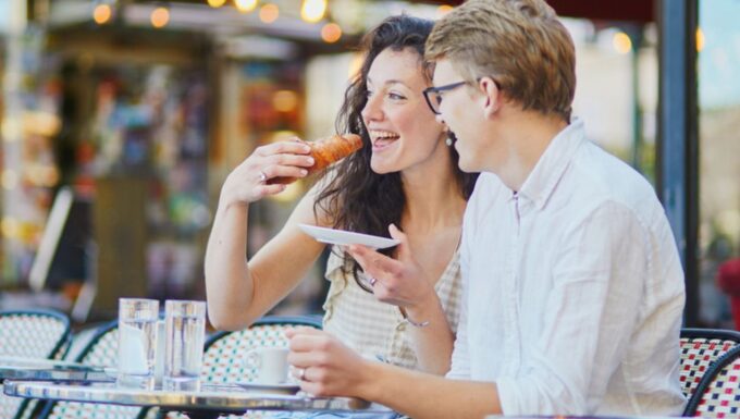 Happy romantic couple in Paris, drinking coffee in traditional Parisian outdoor cafe. Tourists spending their vacation in France